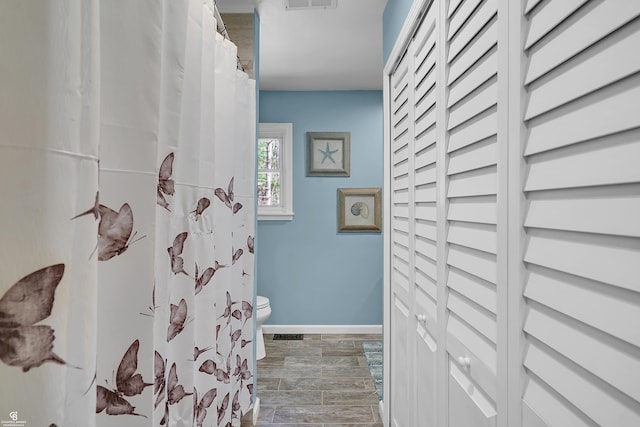 bathroom featuring toilet, curtained shower, visible vents, and baseboards