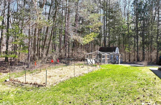 view of yard featuring exterior structure, an outdoor structure, and a wooded view