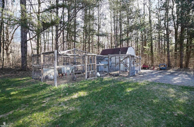 view of yard featuring exterior structure, an outbuilding, and a wooded view