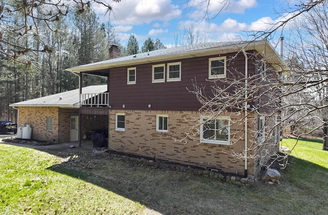 back of property with brick siding, a yard, and a chimney