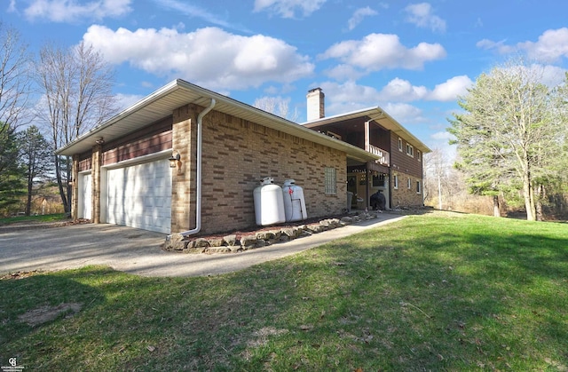 view of side of home featuring a chimney, driveway, a yard, a garage, and brick siding