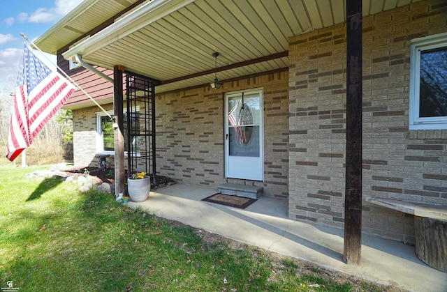doorway to property featuring brick siding and a yard
