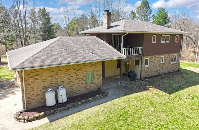 back of property featuring a patio area, a shingled roof, a chimney, and a yard