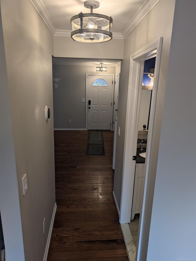 doorway with wood finished floors, crown molding, and baseboards