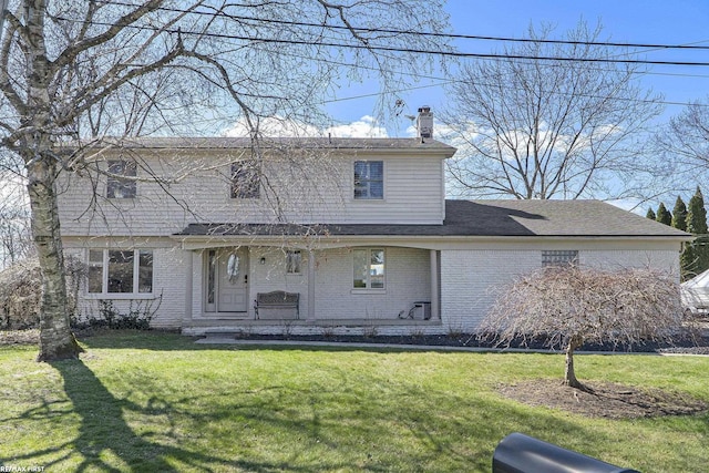 back of property featuring a yard, a porch, brick siding, and a chimney
