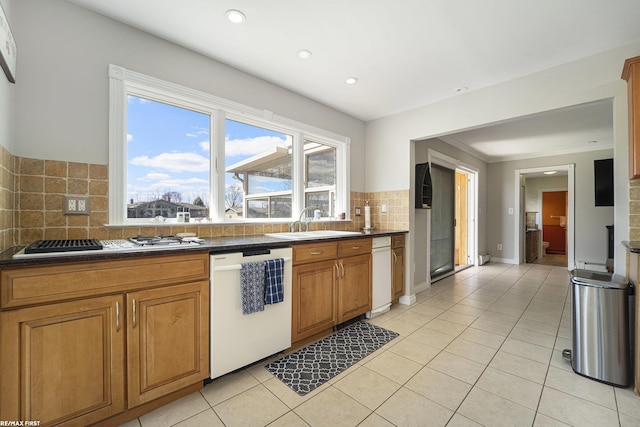 kitchen with white appliances, decorative backsplash, a sink, and dark countertops