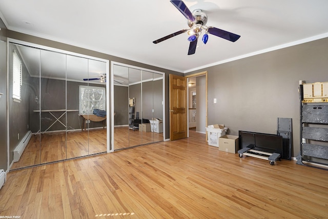 bedroom with baseboard heating, a ceiling fan, crown molding, multiple closets, and wood-type flooring