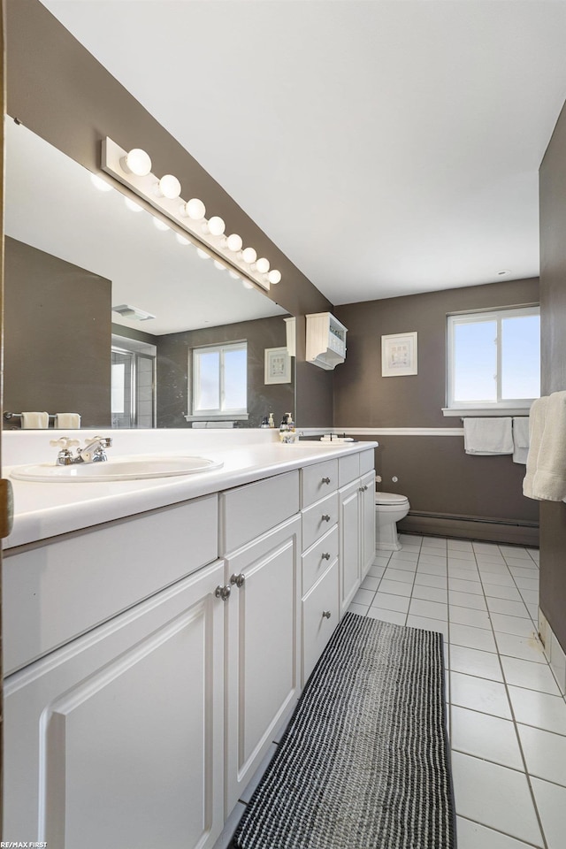 bathroom with toilet, double vanity, a sink, and tile patterned flooring