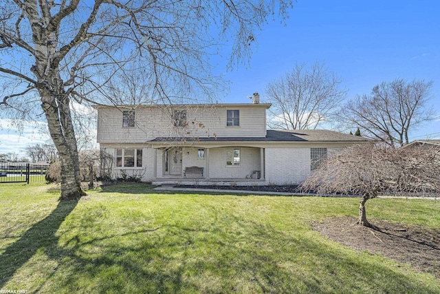 traditional home with brick siding, a front lawn, fence, and a chimney