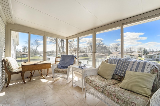sunroom / solarium with a water view, tile patterned floors, vaulted ceiling, and an outdoor hangout area