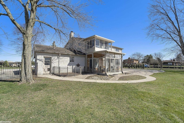 back of property with fence, a yard, a sunroom, and a chimney