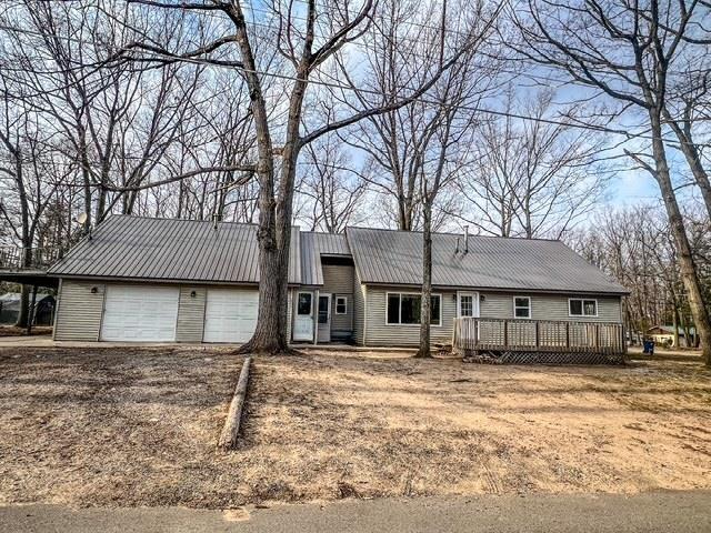 view of front of property featuring an attached garage, metal roof, and a deck