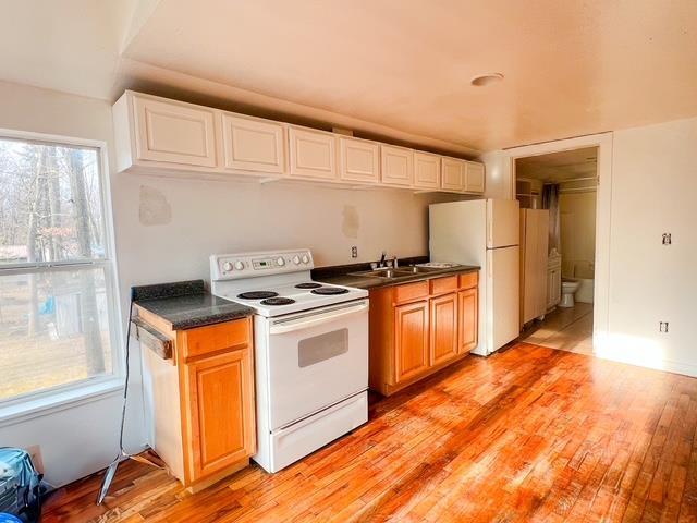 kitchen featuring dark countertops, a healthy amount of sunlight, white appliances, and light wood-type flooring