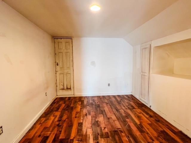bonus room featuring dark wood finished floors, lofted ceiling, and baseboards