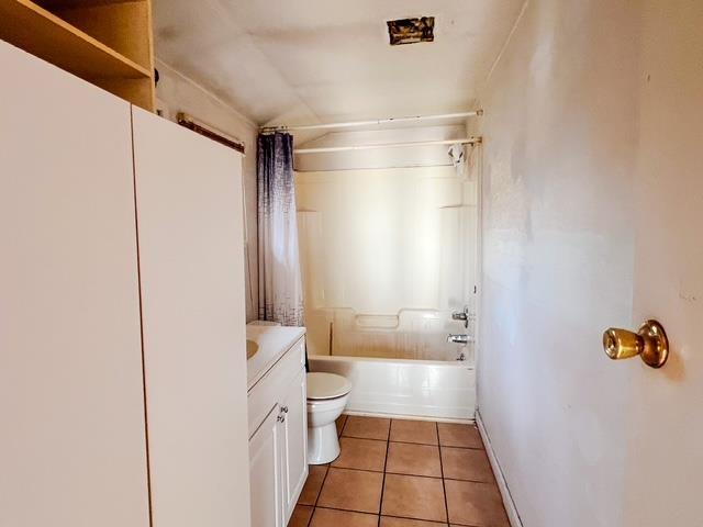 bathroom featuring tile patterned floors, shower / bath combo with shower curtain, vanity, and toilet