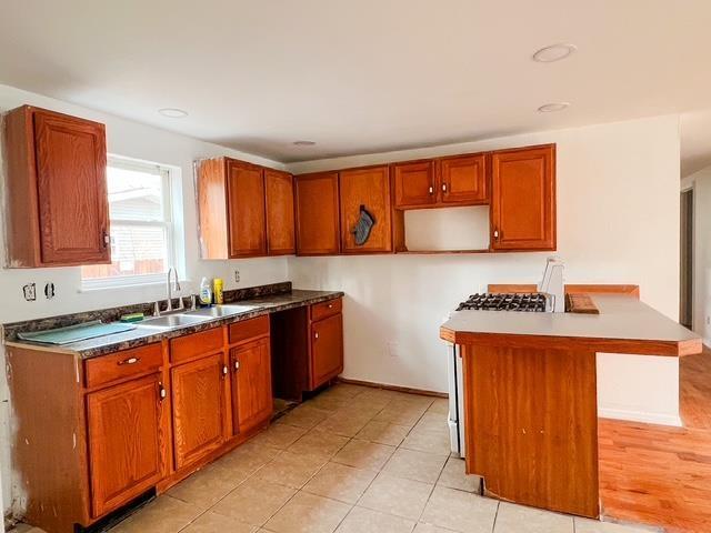 kitchen with dishwasher, brown cabinetry, and a sink