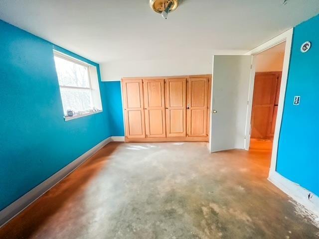 unfurnished bedroom featuring concrete flooring and baseboards