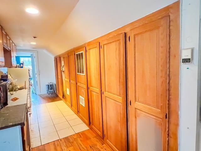corridor with vaulted ceiling and light wood-style floors