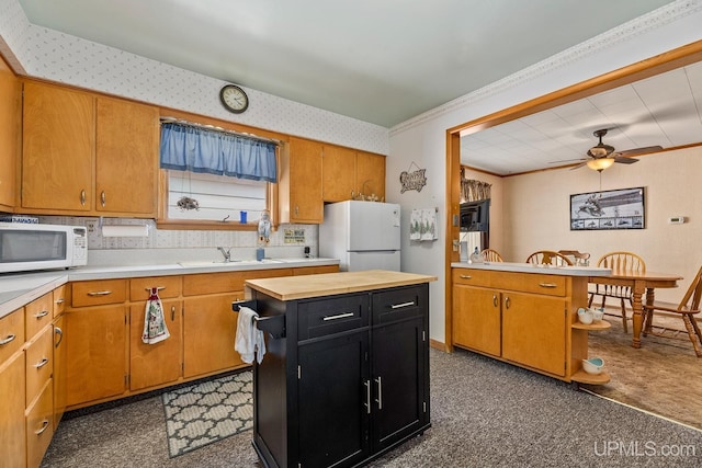kitchen featuring a sink, a ceiling fan, white appliances, dark cabinets, and ornamental molding