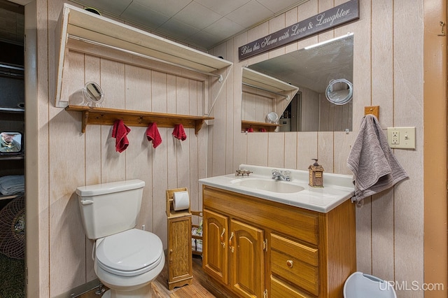 bathroom with wood finished floors, toilet, vanity, and wood walls