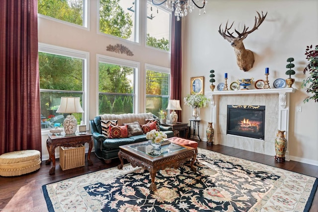 living area with an inviting chandelier, a tile fireplace, wood finished floors, and a wealth of natural light