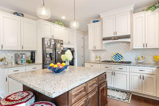 kitchen with light stone counters, tasteful backsplash, appliances with stainless steel finishes, under cabinet range hood, and dark wood-type flooring