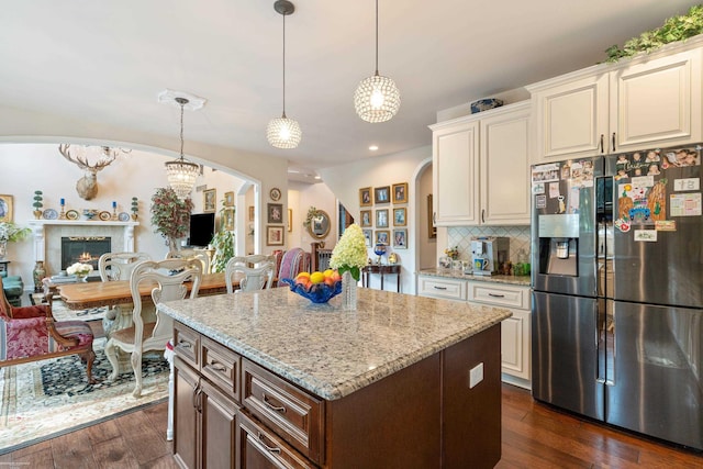kitchen with arched walkways, dark wood-type flooring, stainless steel refrigerator with ice dispenser, and open floor plan