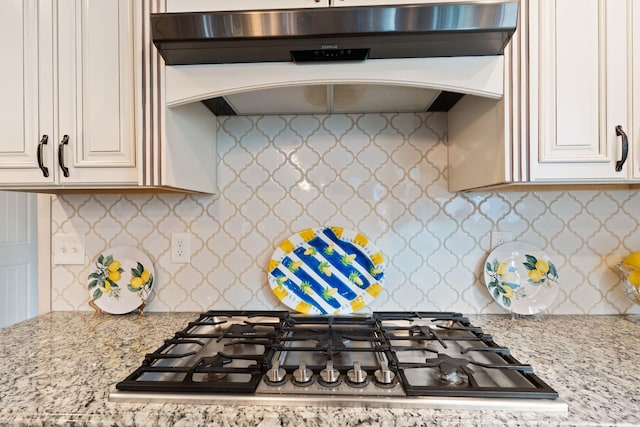kitchen featuring stainless steel gas cooktop, light stone counters, white cabinetry, and custom range hood