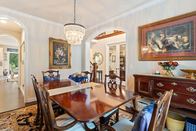dining space with french doors, wood finished floors, arched walkways, and a notable chandelier