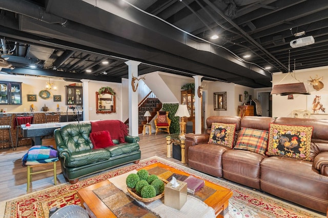 living room with bar area, wood finished floors, stairs, and ornate columns