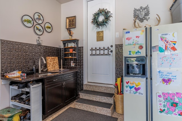 kitchen featuring a sink, dark stone countertops, backsplash, white refrigerator with ice dispenser, and open shelves