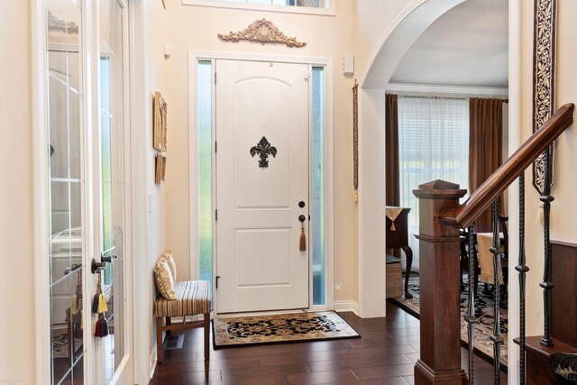 entryway featuring baseboards, dark wood-style floors, and arched walkways