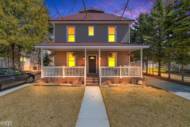 view of front of home with covered porch, a yard, and metal roof