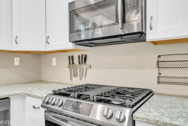 kitchen featuring white cabinets, light stone counters, and stainless steel appliances