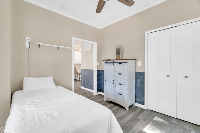 bedroom featuring wood finished floors, a closet, crown molding, baseboards, and ceiling fan