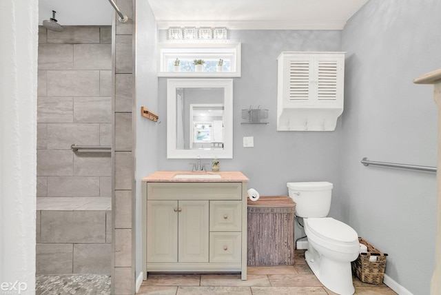 full bathroom with baseboards, vanity, toilet, and tiled shower