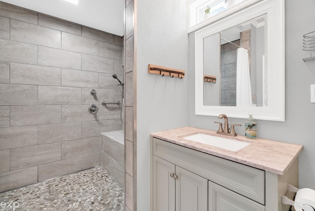 full bathroom featuring vanity and tiled shower
