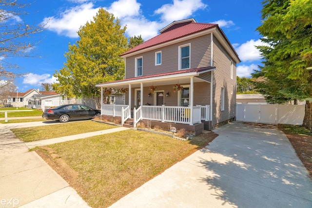 view of front of house featuring a gate, metal roof, concrete driveway, covered porch, and a front yard