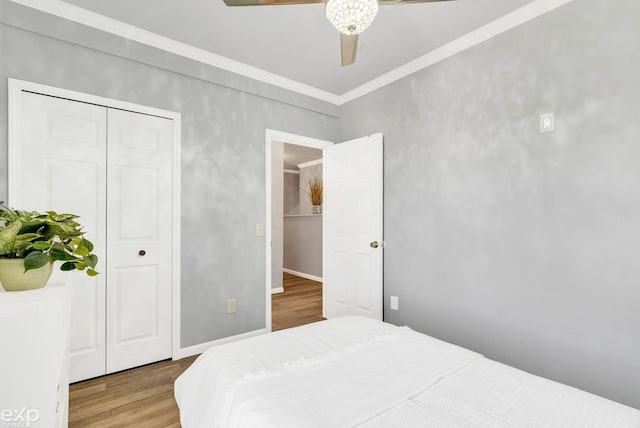 bedroom with a ceiling fan, wood finished floors, a closet, baseboards, and ornamental molding