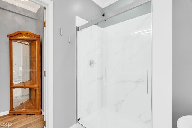 full bath featuring wood finished floors, ornamental molding, baseboards, and a marble finish shower