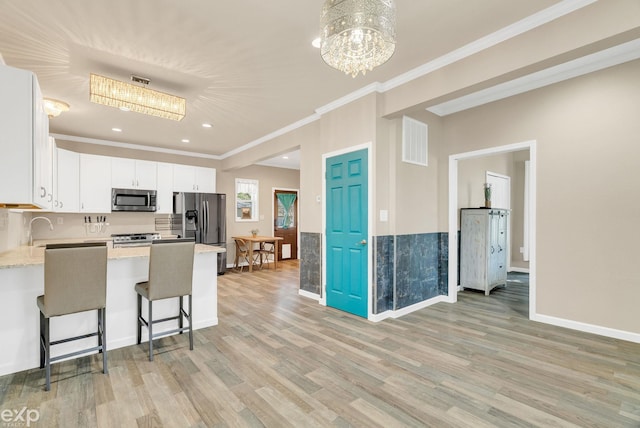 kitchen featuring stainless steel appliances, visible vents, ornamental molding, a peninsula, and a chandelier