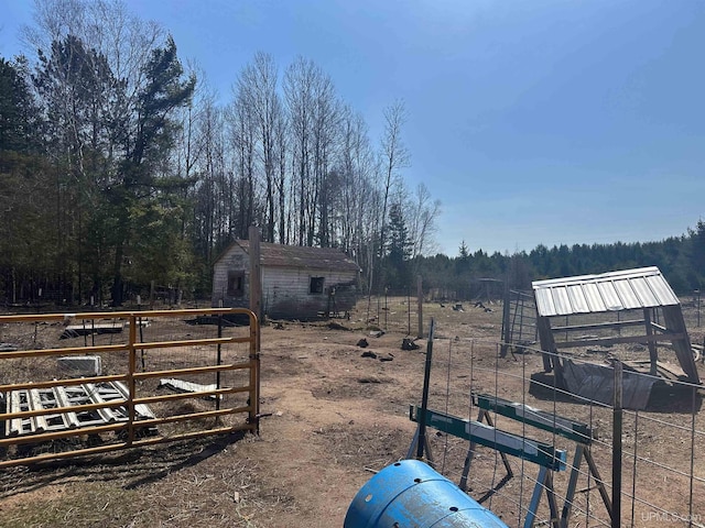 view of yard with a view of trees, an outbuilding, and fence
