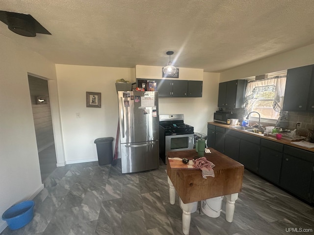 kitchen with a sink, decorative light fixtures, baseboards, a textured ceiling, and appliances with stainless steel finishes