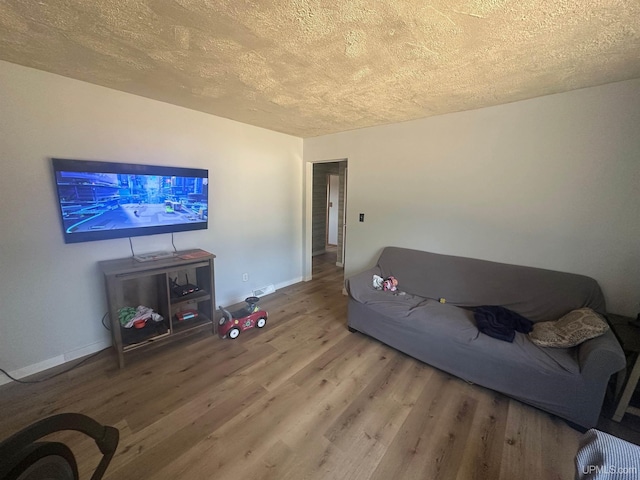 living area featuring baseboards, wood finished floors, and a textured ceiling