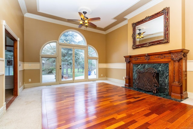 unfurnished living room with a premium fireplace, wood finished floors, ceiling fan, and crown molding