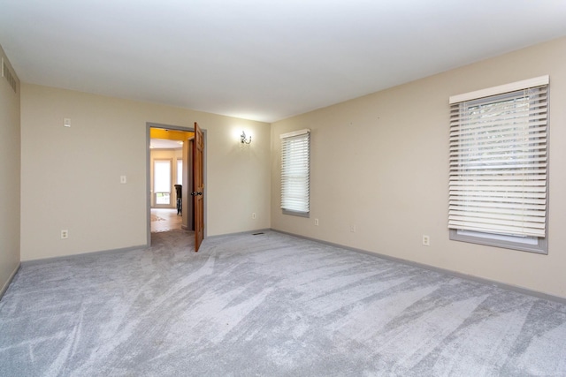 unfurnished room with baseboards and light colored carpet