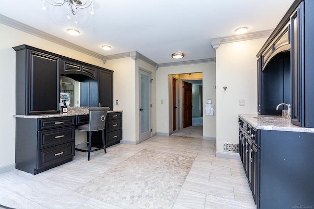 interior space with baseboards, crown molding, a sink, and built in desk