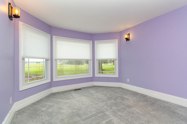 spare room with baseboards, visible vents, and carpet floors