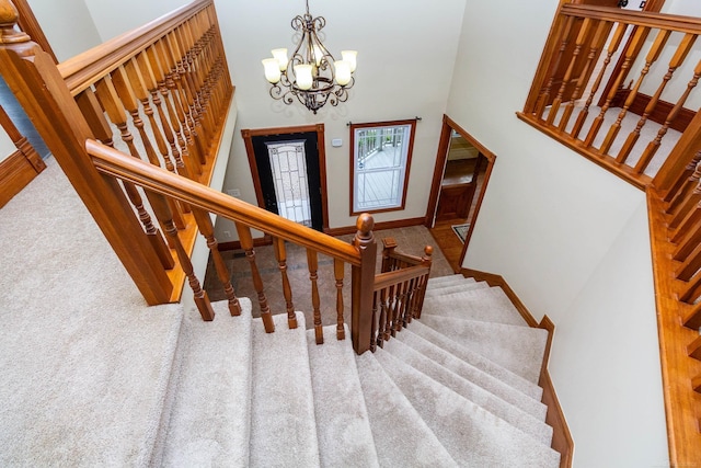 stairway with a chandelier, carpet, a high ceiling, and baseboards