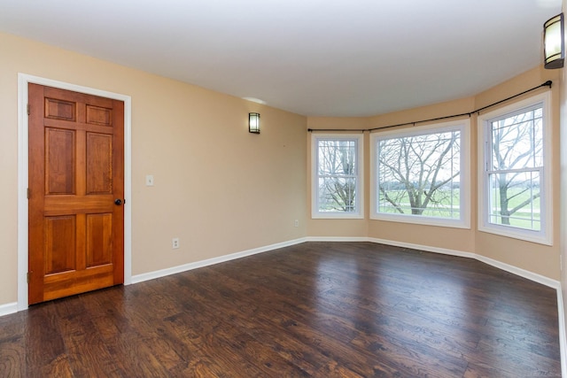 unfurnished room with dark wood finished floors, visible vents, and baseboards